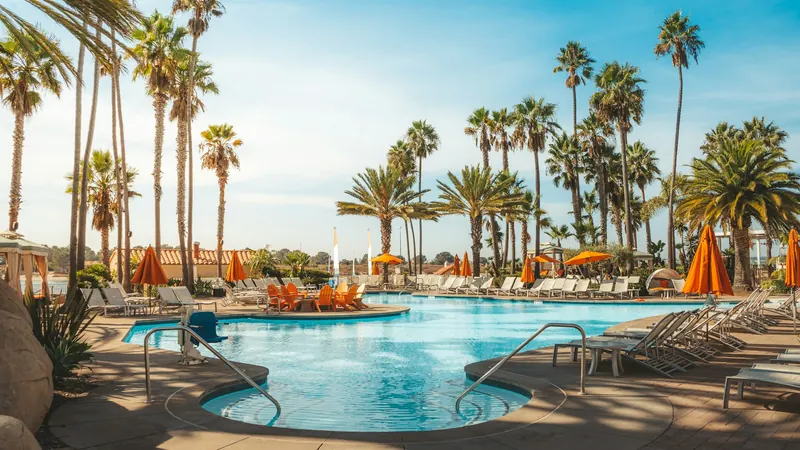 A resort swimming pool surrounded by palm trees and loungers
